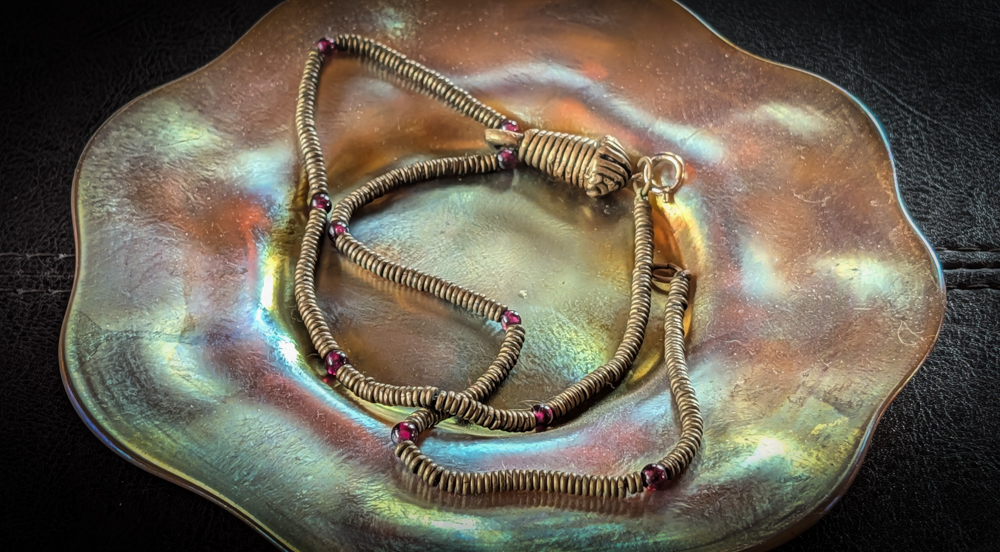 Brass and garnet necklace on a Tiffany saucer